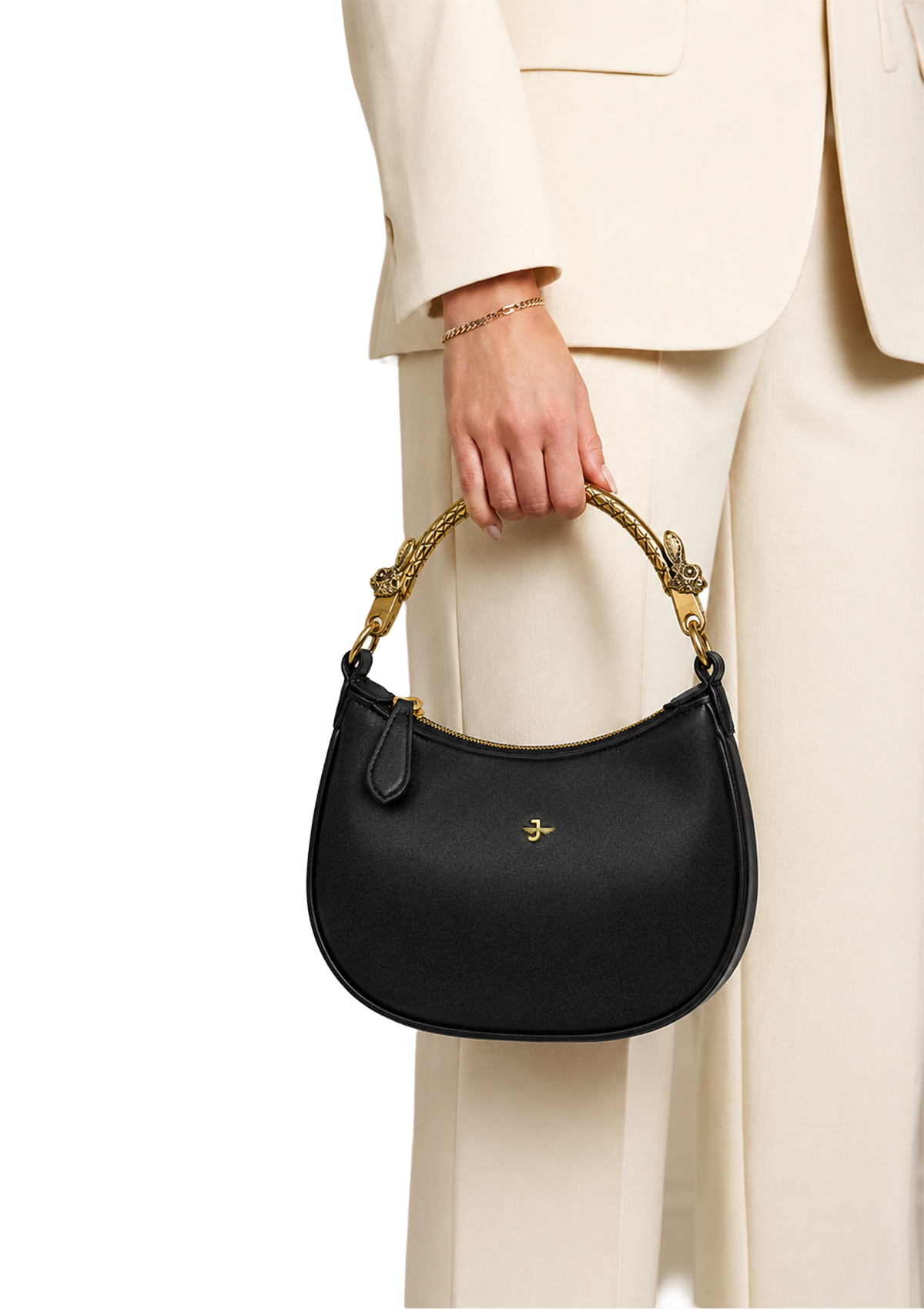 Black handbag with gold handle held by a person wearing a beige suit on a white background